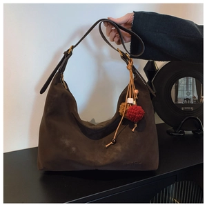 Detail of dark brown suede hobo bag featuring adjustable strap and colorful charm