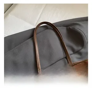 Detail showing the comfortable dark brown leather handle and fine stitching of the tote