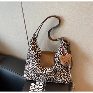 Détail du sac léopard en toile avec rabat en cuir brun et pendentif ours en peluche