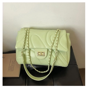 Close-up of light green quilted crossbody bag with metal twist lock and chain strap