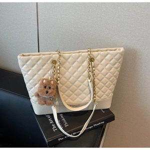 Détail du sac cabas blanc matelassé avec chaîne dorée et breloque ours en peluche