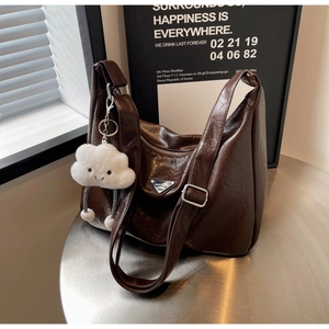 Detail of coffee brown pleated shoulder bag with metallic logo and cute plush charm
