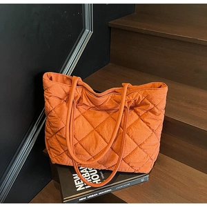Détail du grand sac cabas matelassé orange à motif losanges sur un escalier