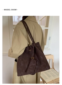 Detail of dark brown suede tote bag with small coin purse and golden logo lettering