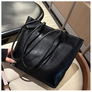 Detailed macro view of the black tote bag with unique wrinkled leather texture and slim straps