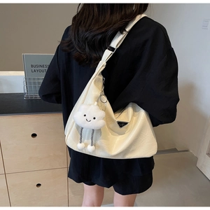 Detail of cream pleated shoulder bag with silver triangle logo and plush cloud charm