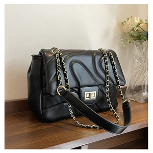 Detail of the golden twist lock and wave quilted pattern on the black crossbody bag