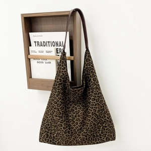 Détail du sac seau en daim à imprimé léopard avec bandoulière en cuir sur un support