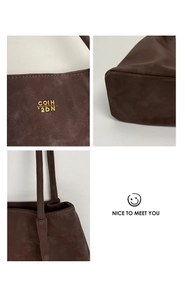 Detail view of dark brown suede tote bag with golden COIH 2DN logo and textured handle