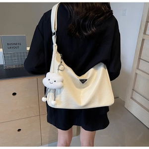 Detail of cream textured PU leather shoulder bag with a cloud pendant on model