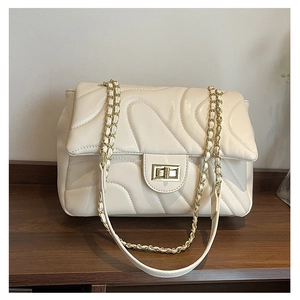 Detail of cream quilted leather flap bag featuring elegant gold twist lock and chain strap