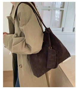 Detail of dark brown suede tote bag with mini coin purse shown on a model's shoulder