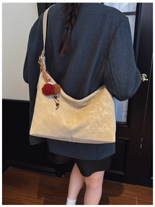 Detail of cream suede hobo bag featuring Merfil logo and decorative plush charm