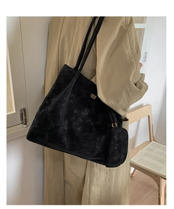 Detail of a black matte suede tote bag with golden logo and matching small pouch