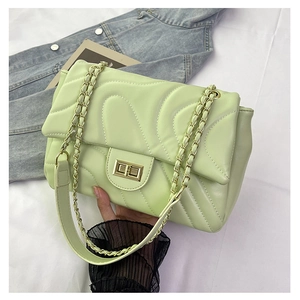 Close-up of mint green quilted leather bag with wave stitching and gold chain strap