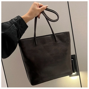 Detail view of smooth dark brown leather texture on a spacious commuter tote bag