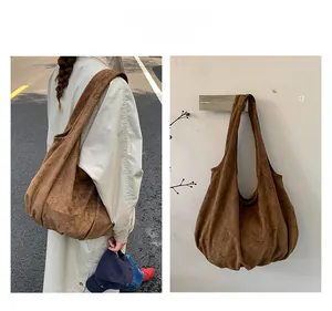 Detailed view of brown suede hobo tote bag featuring slouchy design and pleated bottom texture