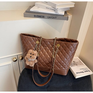 Détail du sac cabas matelassé marron avec chaîne dorée et breloque ours en peluche
