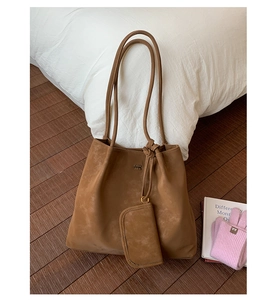 Detail of a brown suede tote bag with small matching pouch on a cozy home background