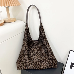 Gros plan du sac cabas à imprimé léopard avec poignées en cuir marron dans un décor chaleureux