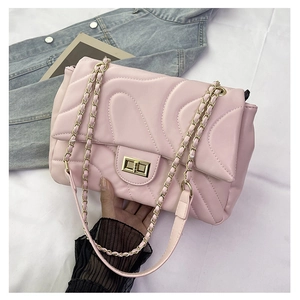 Detail of pink quilted flap bag with golden twist lock and chain shoulder strap