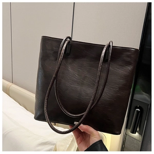 Close-up of deep brown tote bag featuring vintage leather texture and slim double straps