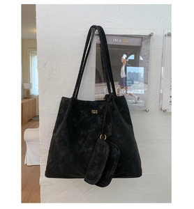 Detail of black suede tote bag featuring golden COIN 2DN logo and small attached pouch