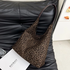 Vue détaillée du sac hobo imprimé léopard posé sur une surface en cuir noir élégante