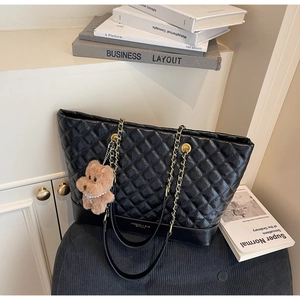Détail du sac cabas matelassé noir avec chaîne dorée et breloque peluche chiot marron