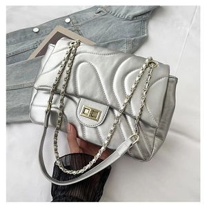 Detail of silver quilted crossbody bag with gold lock and metal chain strap