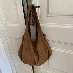 Close-up of brown suede hobo bag showing large capacity and soft pleated texture