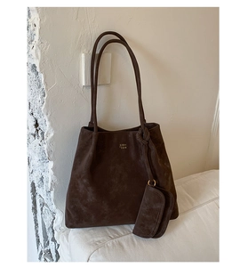 Macro detail of dark brown suede tote bag featuring a knotted tassel and logo