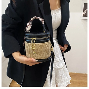 Detail einer Mini-Zylindertasche mit schickem Seidenschal-Griff und Blumenanhänger-Akzenten
