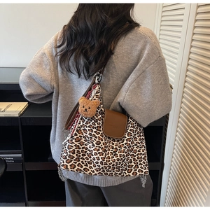 Détail du sac cabas léopard avec rabat en cuir marron et breloque ours en peluche