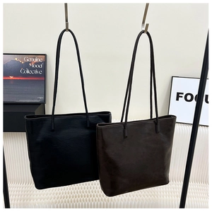 Detail view of large tote bags in black and dark brown with premium oil-leather texture
