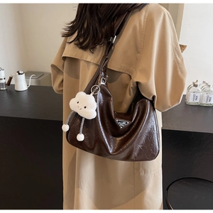 Détail du sac hobo en cuir froissé marron foncé avec bandoulière et pendentif peluche