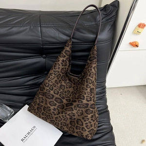Détail du sac seau en daim à motif léopard avec bandoulière en cuir sur fauteuil