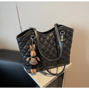 Close-up of black quilted tote bag with rabbit charm and printed Fashion Bag text