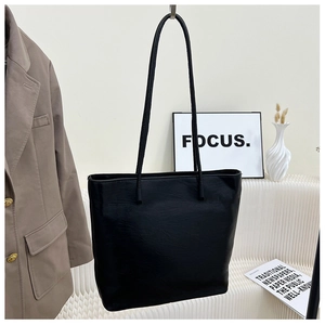 Close-up of minimalist black leather tote bag with fine texture and slim straps for women