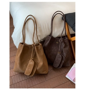 Detail of camel and dark brown suede tote bags with gold logo and matching mini pouches