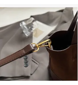 Detail of dark brown bucket bag featuring gold hardware and matte suede leather texture