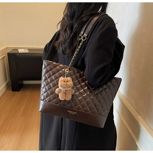 Détail du sac cabas matelassé marron avec chaîne dorée et pendentif ours en peluche
