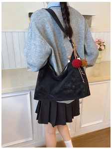 Close-up of black matte hobo bag with MERFIL logo and a decorative plush charm