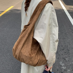 Detail of a brown suede oversized tote bag featuring a wide shoulder strap and soft texture