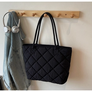 Détail du grand sac cabas noir matelassé avec motif à losanges sur crochet mural
