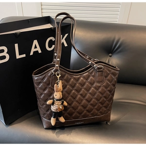 Detail of dark brown quilted tote bag with vintage texture and cute bunny charm accessory