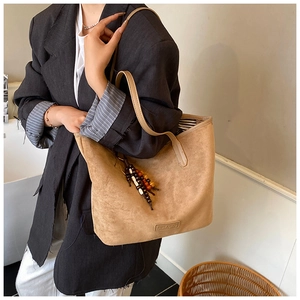 Detail of camel suede tote bag with decorative wooden beads and large interior space