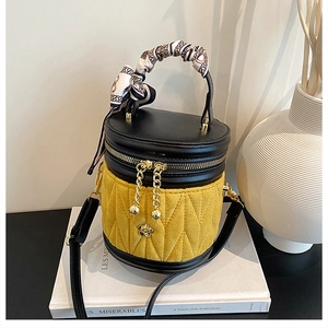 Detail einer gelben gesteppten Beuteltasche mit schwarzem Leder und Seidenschal-Griff