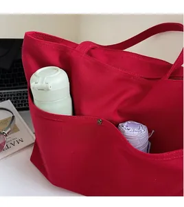 Close-up of red canvas tote with external pocket holding a water bottle and umbrella