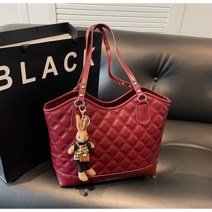 Detailed view of dark red quilted tote bag with diamond pattern and bunny charm